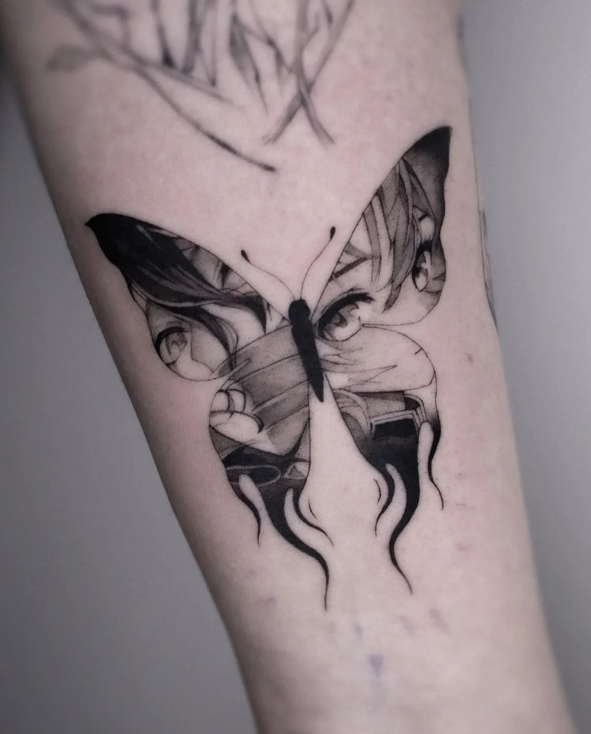 Schmetterling Tattoo mit Anime-Augen und Flammen im Blackwork-Stil am Unterarm
