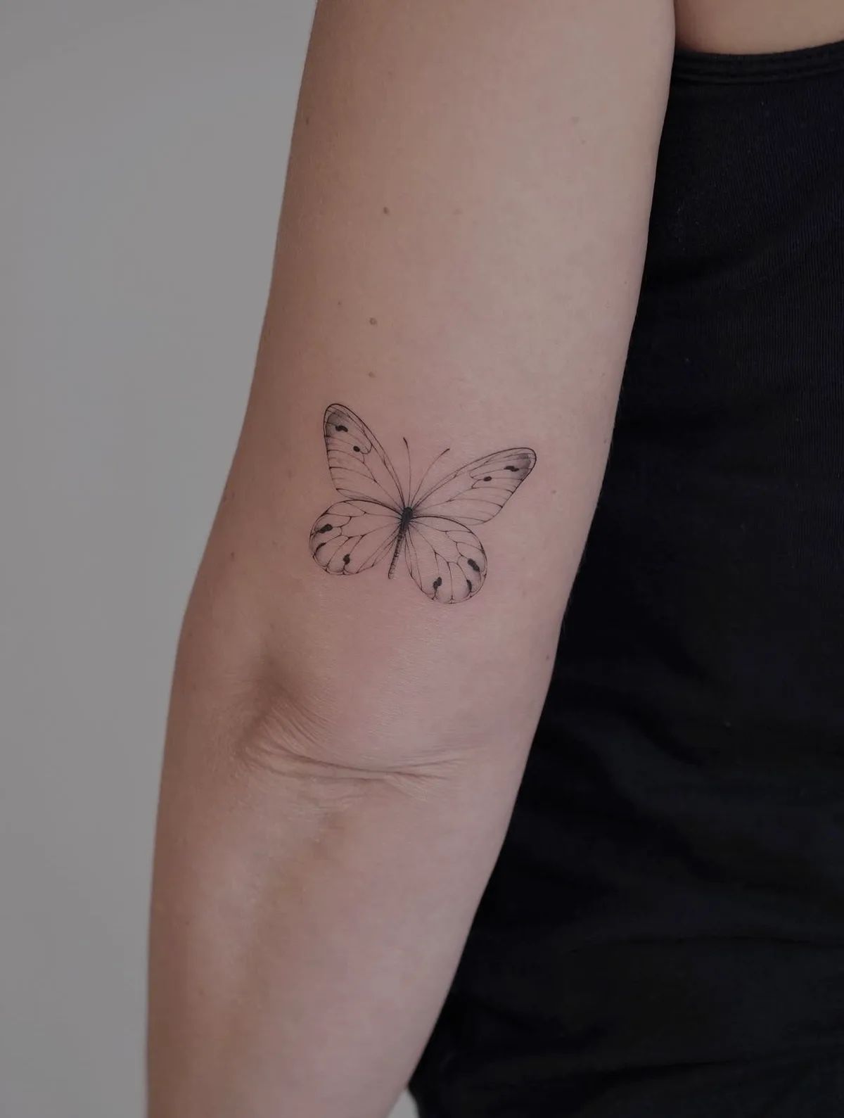 Schmetterling Tattoo Fineline am Oberarm