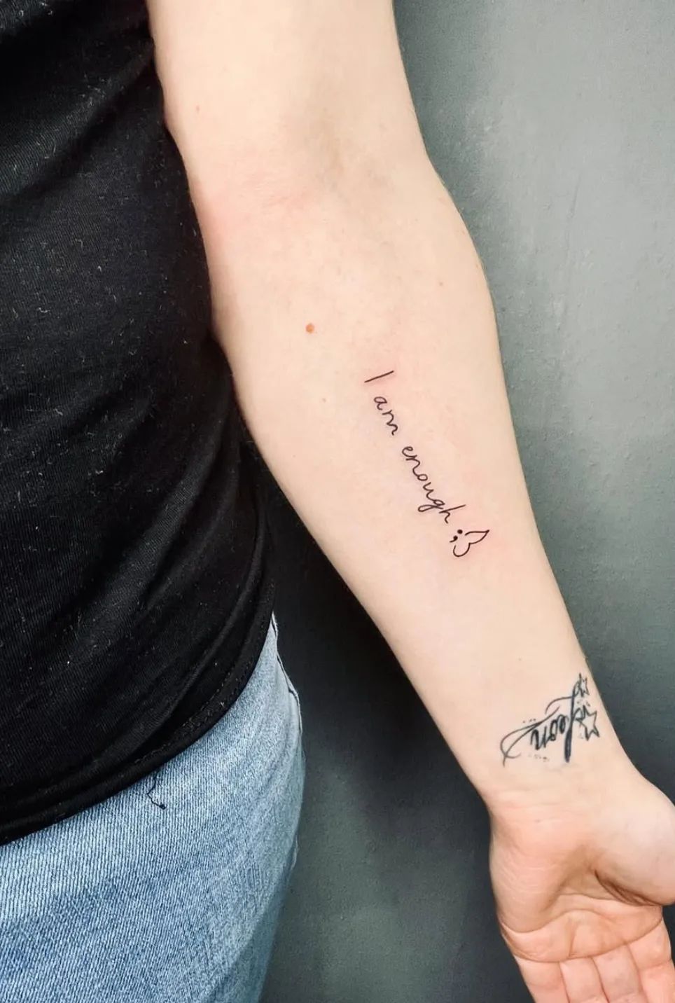 Lettering tattoo "I am enough" with semicolon heart on forearm