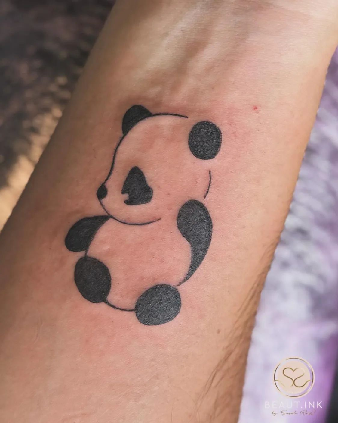 Minimalist panda fine line tattoo on forearm