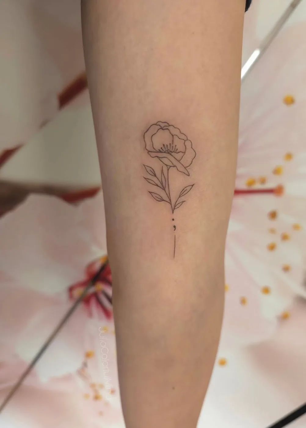 Semicolon tattoo with flower in fine line style on forearm