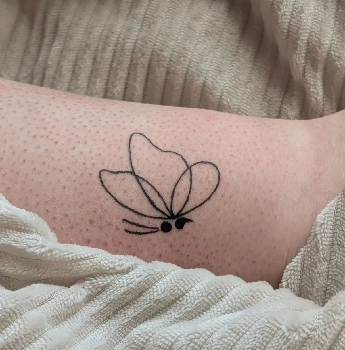 Fine line butterfly semicolon tattoo on leg