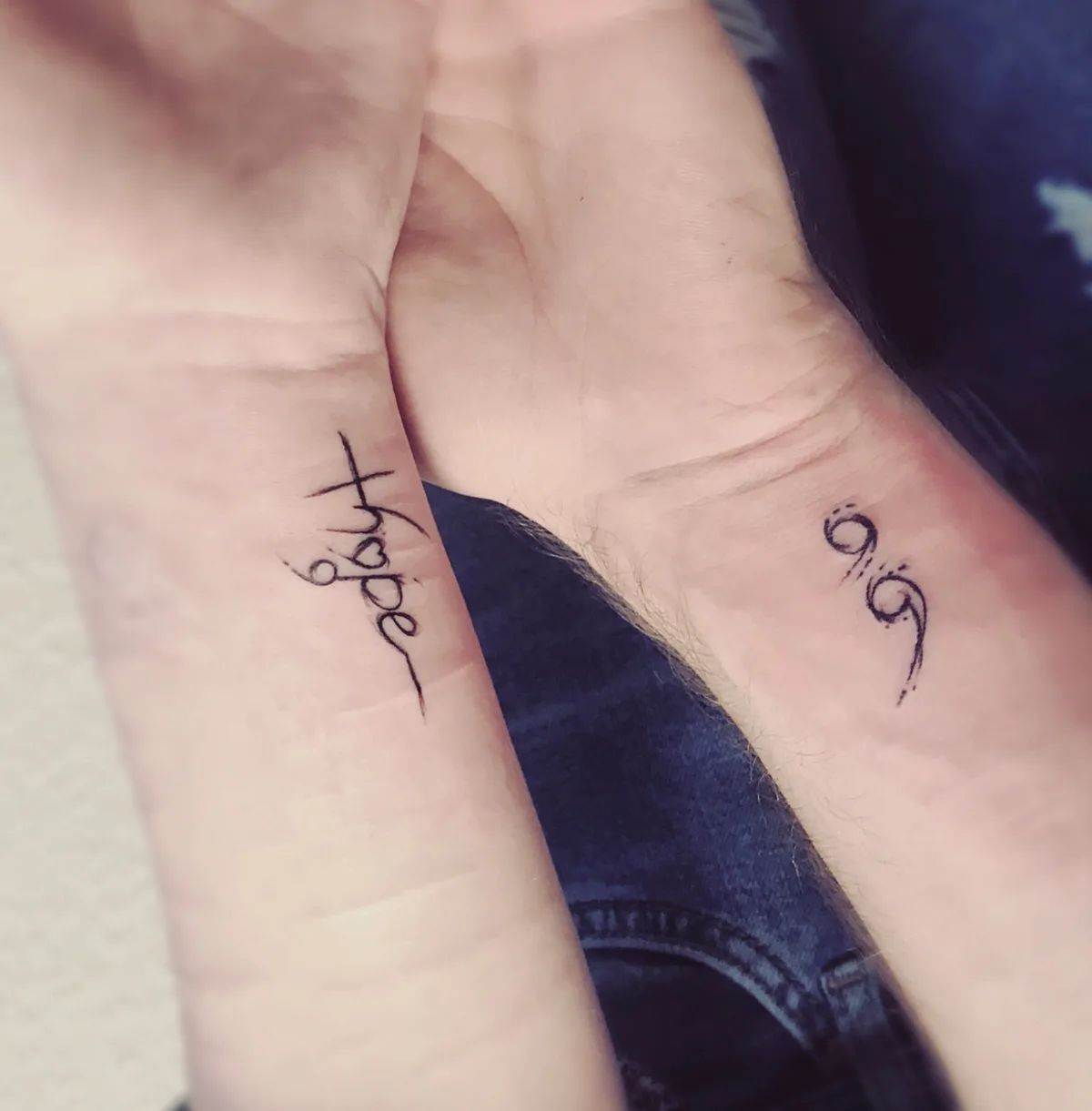 Semicolon tattoo and "hope" lettering as fine line tattoos on the wrist