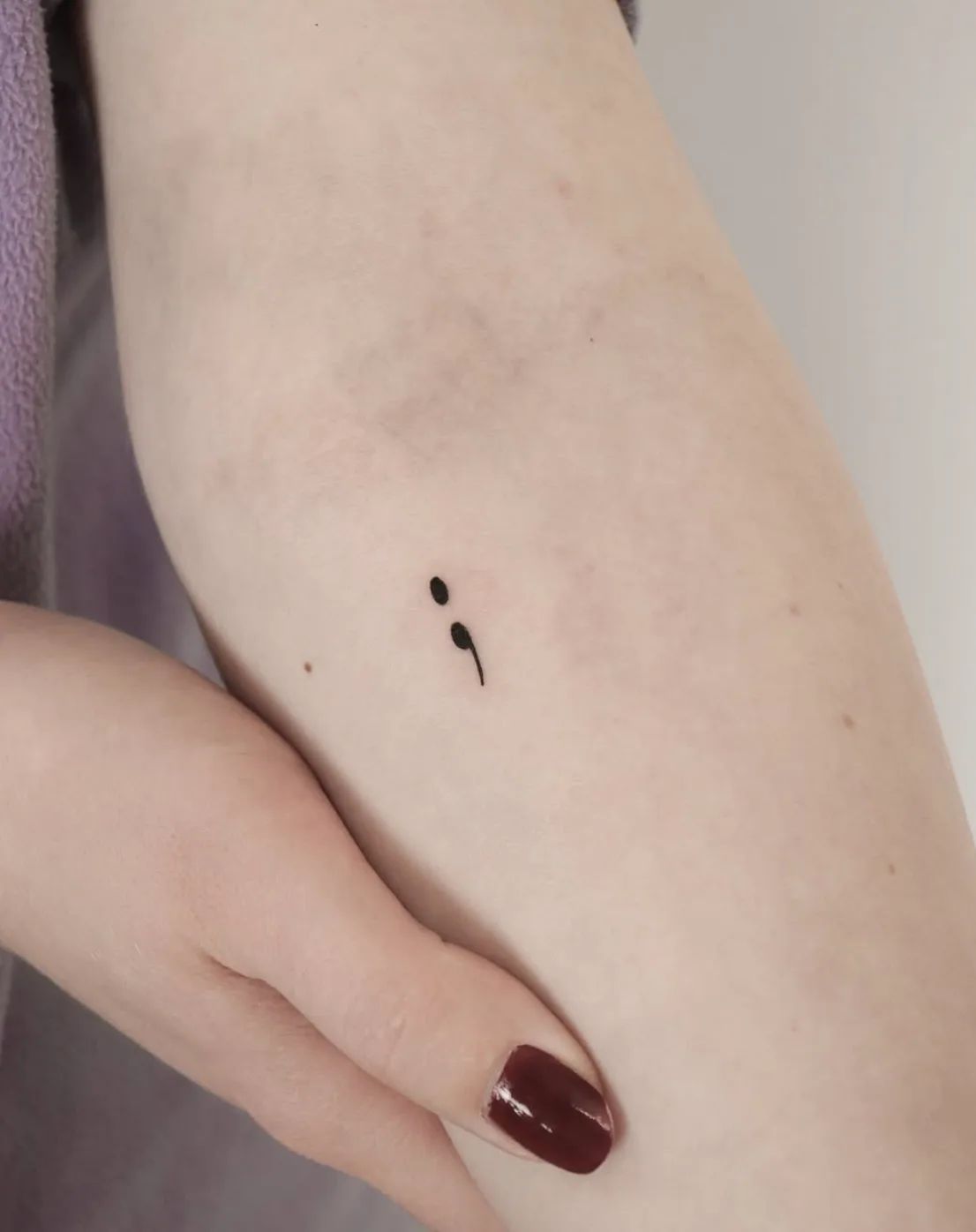 Fine line semicolon tattoo on upper arm
