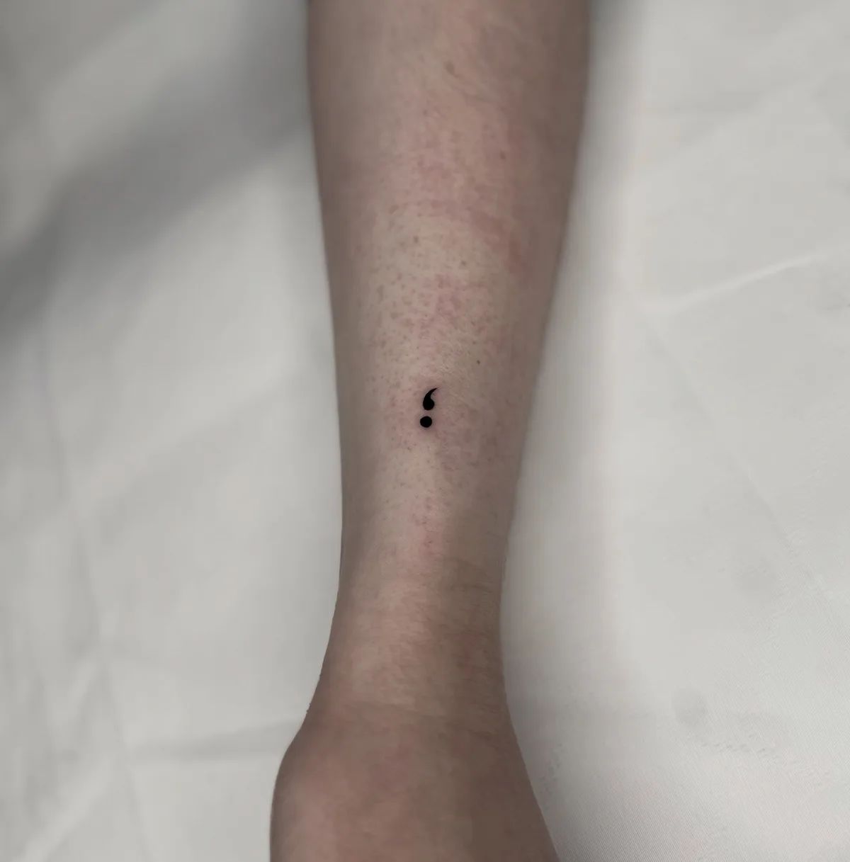 Fine line semicolon tattoo on forearm