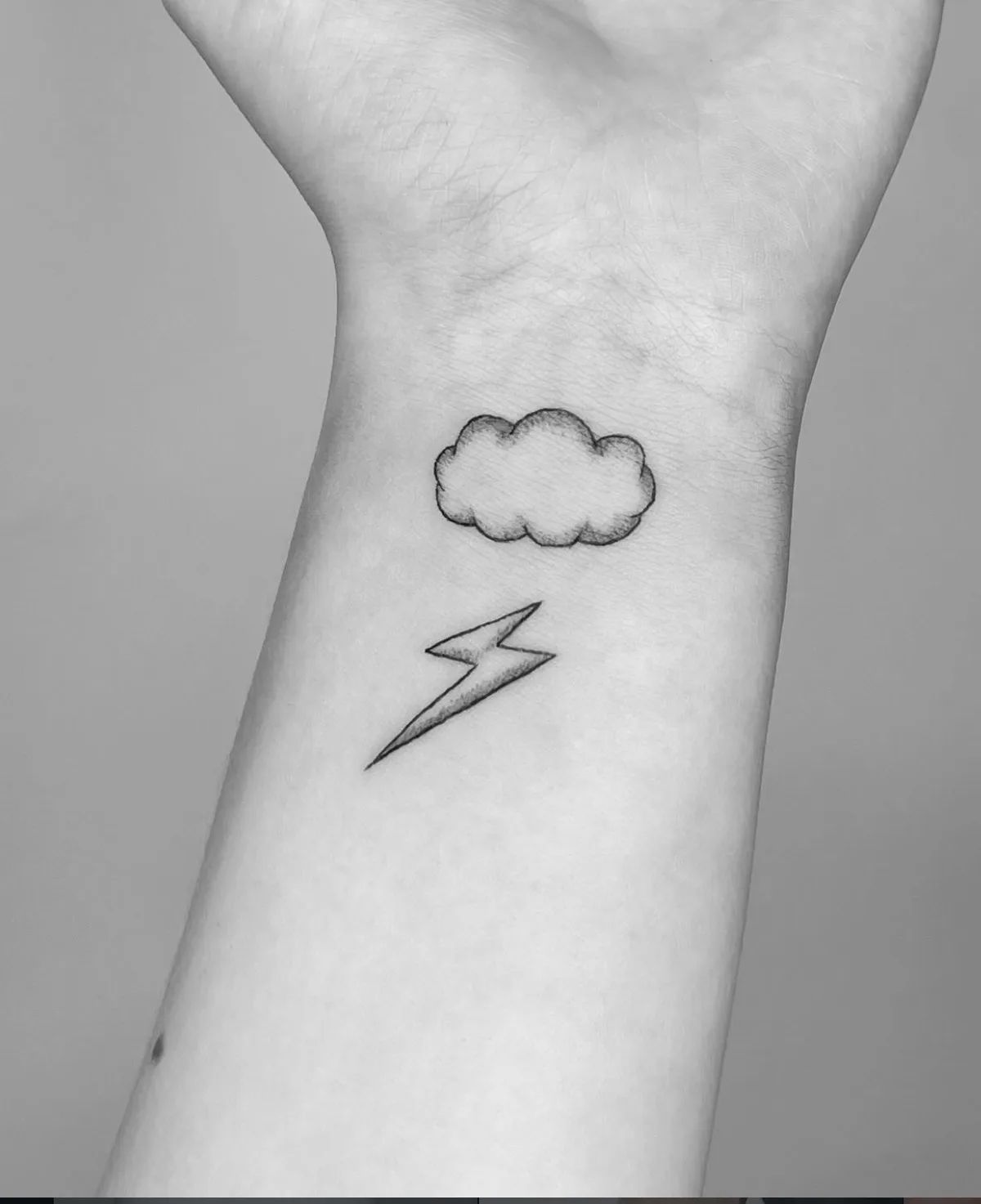 Fine line cloud and lightning bolt tattoo on wrist