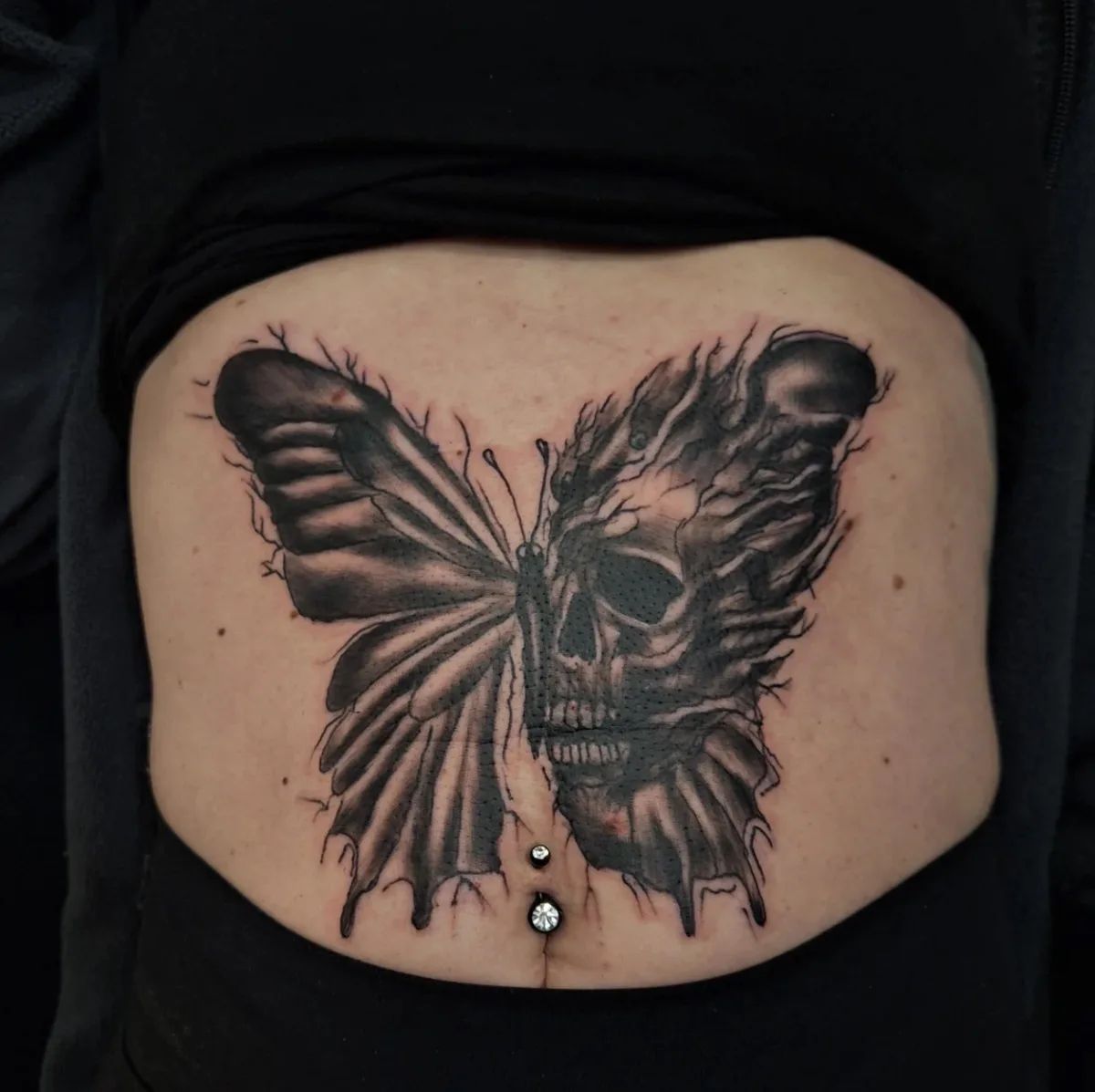 Skull butterfly tattoo in blackwork style on the stomach