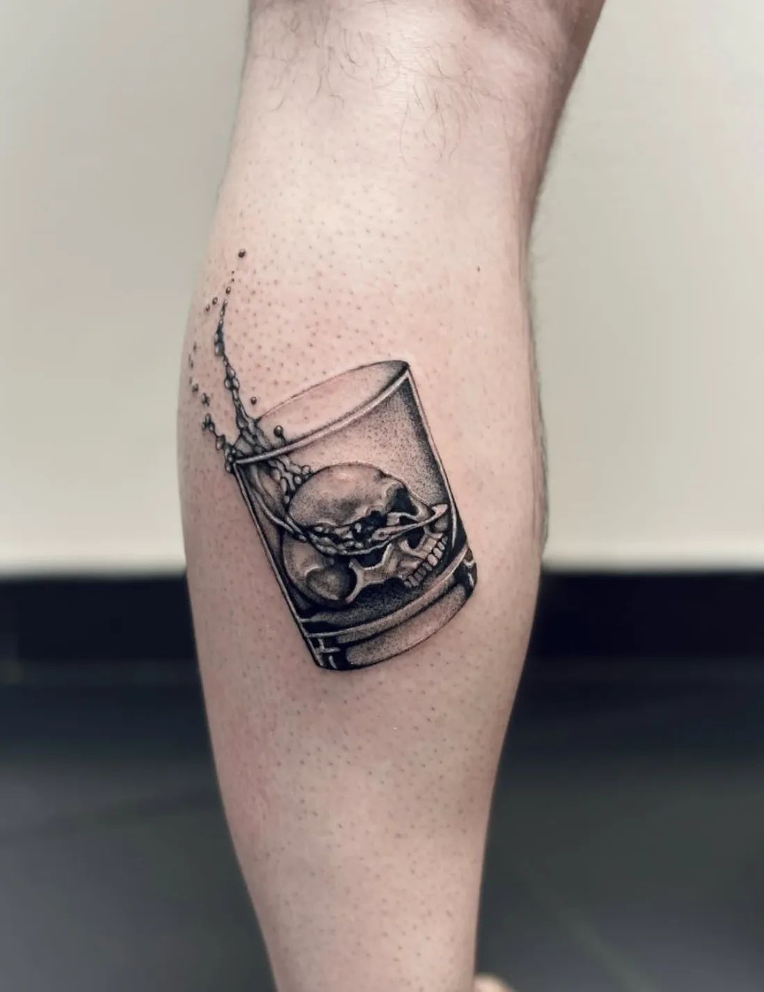 Realistic skull in glass tattoo with water splashes on leg