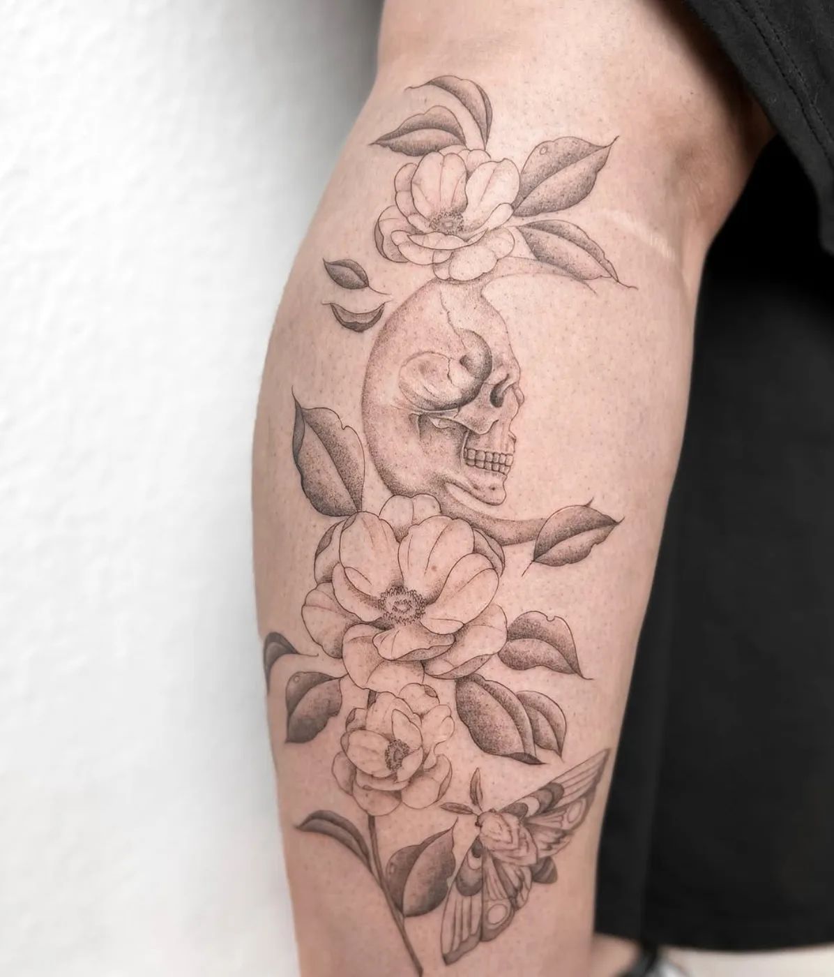 Skull tattoo with flowers and butterfly in fineline style on leg