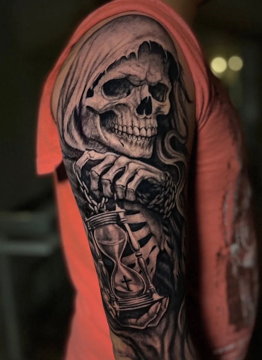 Realistic grim reaper tattoo with hourglass and cross on upper arm