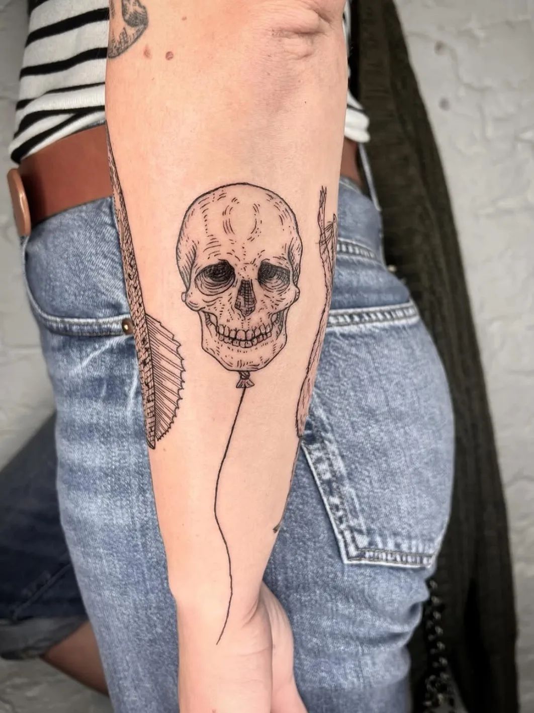 Skull balloon fine line tattoo on forearm