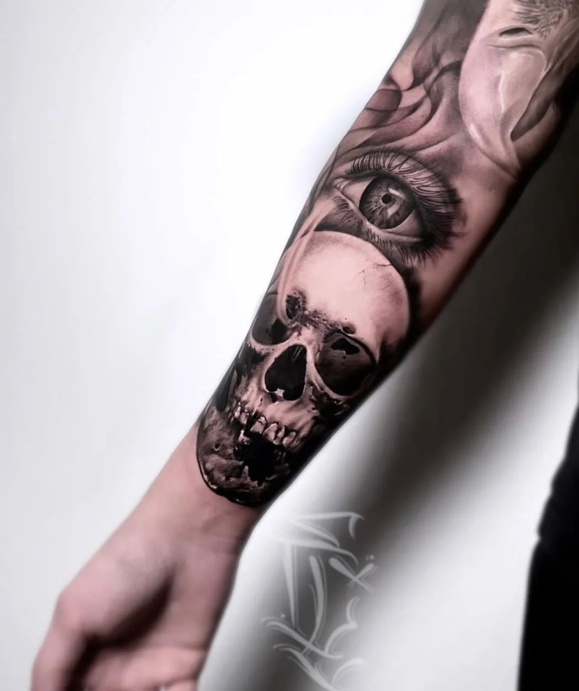 Realistic skull and eye tattoo on forearm in black and grey