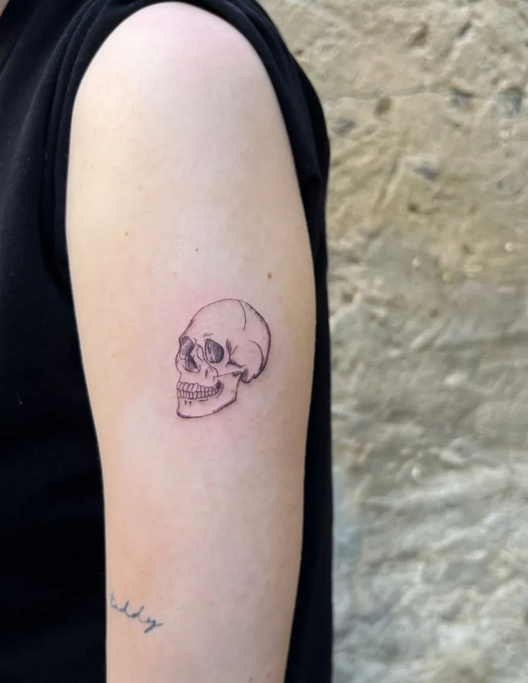 Fine line skull tattoo on upper arm